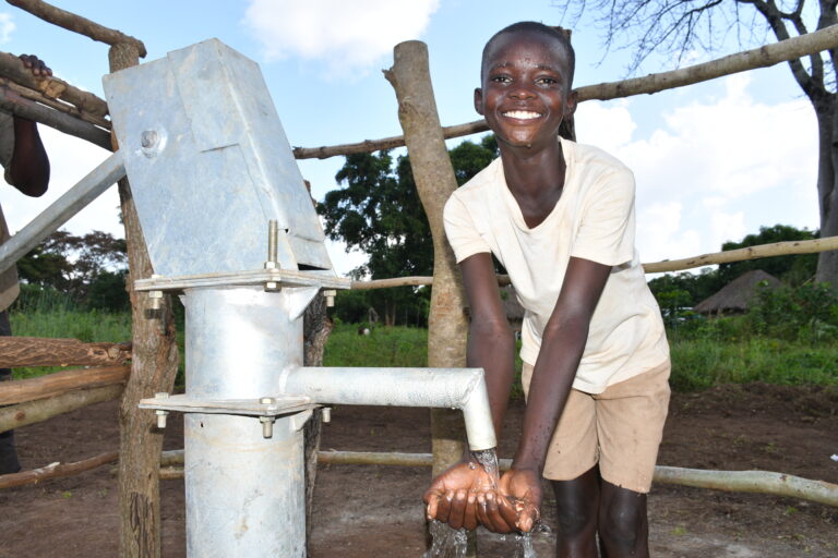 A boy getting water from the new well in Lwokagulu village in Iganga, Uganda