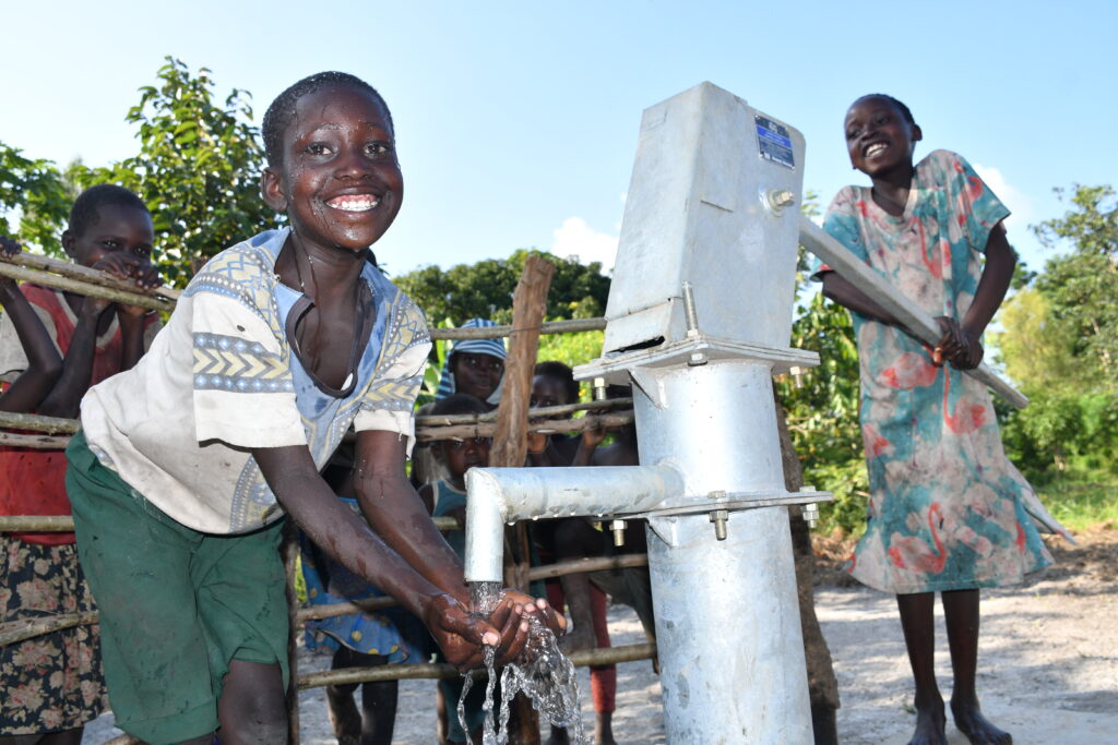 Two Ugandan children from Bidin B village in Nwoya get clean water from a well in the village.