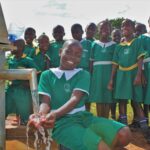 A group of children get clean water from the new well drilled by Drop in the Bucket for the St. Kiziti Good Foundation nursery and primary school in Inanga, Uganda