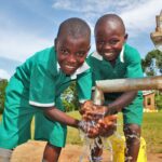 Two boys get clean water from the new well drilled by Drop in the Bucket for the St. Kiziti Good Foundation nursery and primary school in Inanga, Uganda