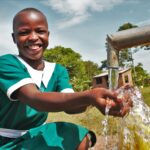 A girl gets clean water from the new well drilled by Drop in the Bucket for the St. Kiziti Good Foundation nursery and primary school in Inanga, Uganda