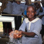 A students gets clean water from the new well at Nawangisa COU primary school in Iganga, Uganda