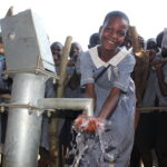 A students gets clean water from the new well at Nawangisa COU primary school in Iganga, Uganda