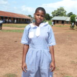 A students stands in front of the classrooms at the Nawangisa COU primary school in Iganga, Uganda