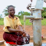 A young girl gets clean water from a water well in Lamin Ayila in Omoro, Uganda drilled by Drop in the Bucket.