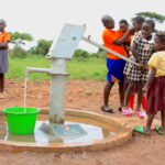 A group of young children getting clean water from a water well in Lamin Ayila in Omoro, Uganda drilled by Drop in the Bucket.