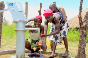 Two women from the village Lamoki in Nwoya, Uganda get clean water from the new well drilled by US water charity Drop in the Bucket.