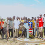 Community members gather around the well in Lamoki, Uganda drilled by US water charity Drop in the Bucket