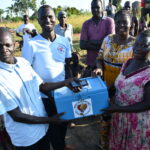 Community members of the VSLA (village savings and loan association) group hold up the lock box that they use to store the funds they collect each week.