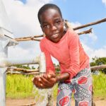 Young boy collecting clean water from a borehole well in Lakuny, Uganda
