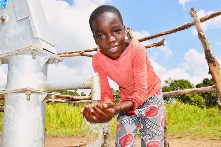 Young boy collecting clean water from a borehole well in Lakuny, Uganda