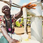 Woman using a community clean water well in Lakuny village, Uganda