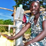A woman gets clean water from a newly drilled well at the Diving Kingdom church in Omoro, Uganda