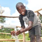 A boy from duddut village in Omoro, Uganda gets clean water from the new well drilled by Drop in the Bucket