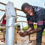 A boy from duddut village in Omoro, Uganda gets clean water from the new well drilled by Drop in the Bucket