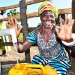 A waving woman from the Awornyim central community in Gulu, Uganda getting clean water from a new borehole 