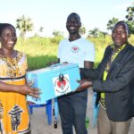 Community members of the Awornyim central  VSLA (village savings and loan association) group hold up the lock box that they use to store the funds they collect each week.