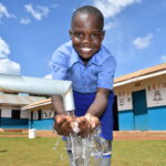 A child gets clean, safe water from a newly drilled well at the God's Glory primary school in Gulu, Uganda