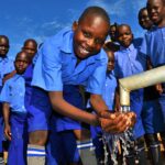 A child gets clean, safe water from a newly drilled well at the God's Glory primary school in Gulu, Uganda