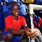 A child gets clean, safe water from a newly drilled well at the God's Glory primary school in Gulu, Uganda