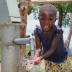 Child getting clean water from the new water well in Opok village in Nwoya, Uganda