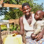 A mother and her child from Kal A 2 Ocega community, getting clean water from the borehole in Nwoya, Uganda