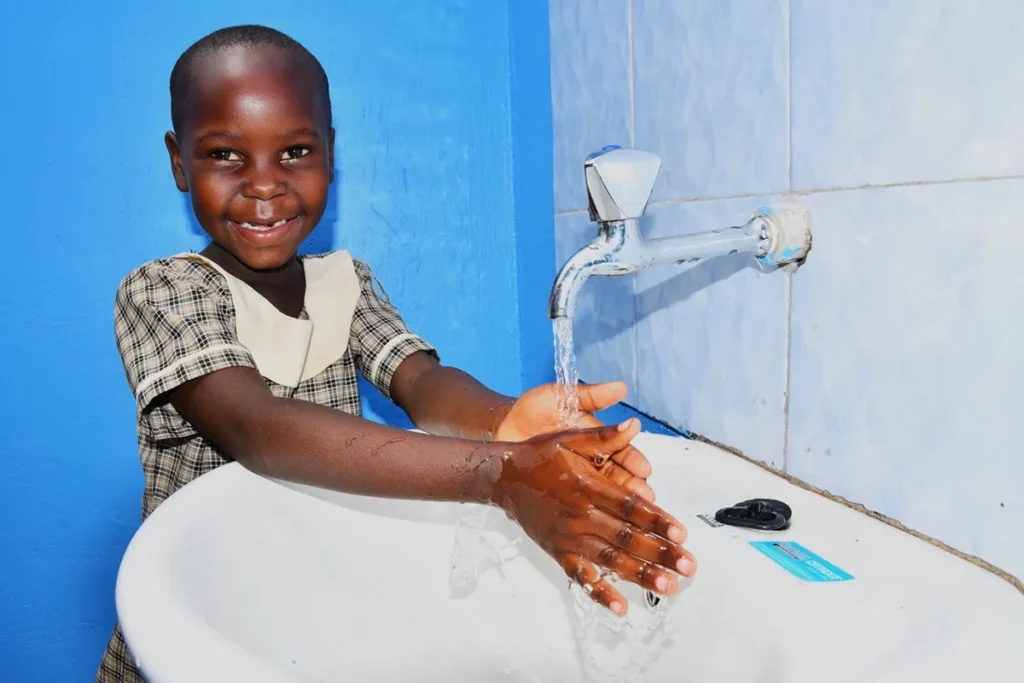 a girl washed her hands at a school in Uganda where Drop in the Bucket built toilets and a well