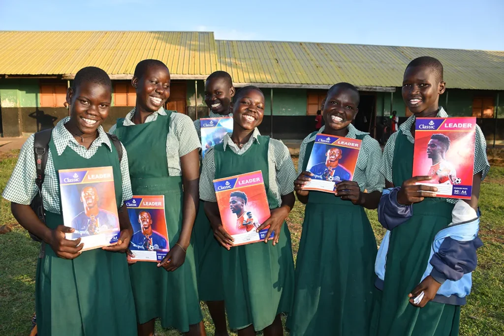 Six REI Primary School girls holding school books at a Drop in the Bucket Safe Space in South Sudan