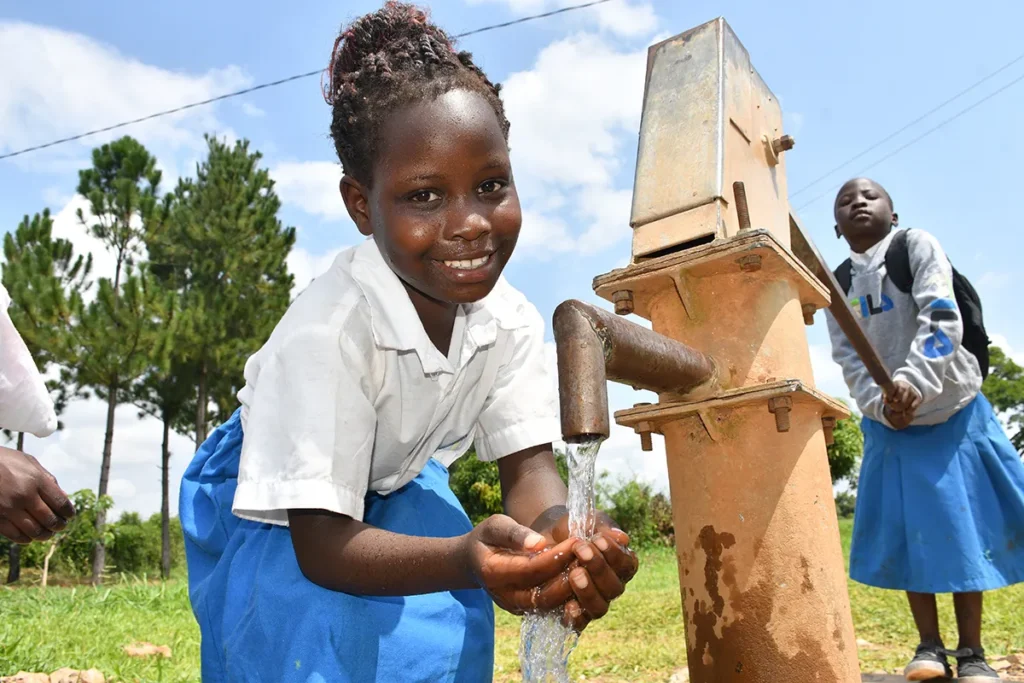Two girls getting clean water from a well in Uganda
