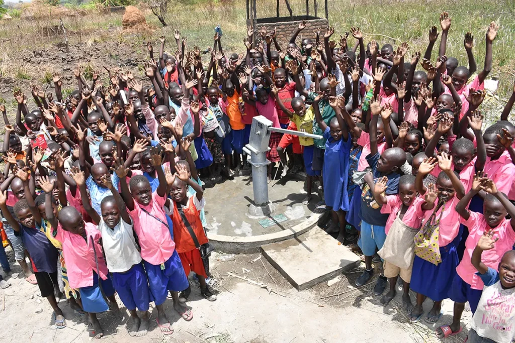 Children from the local community gather around the well drilled by Drop in the Bucket in Ogai Uganda