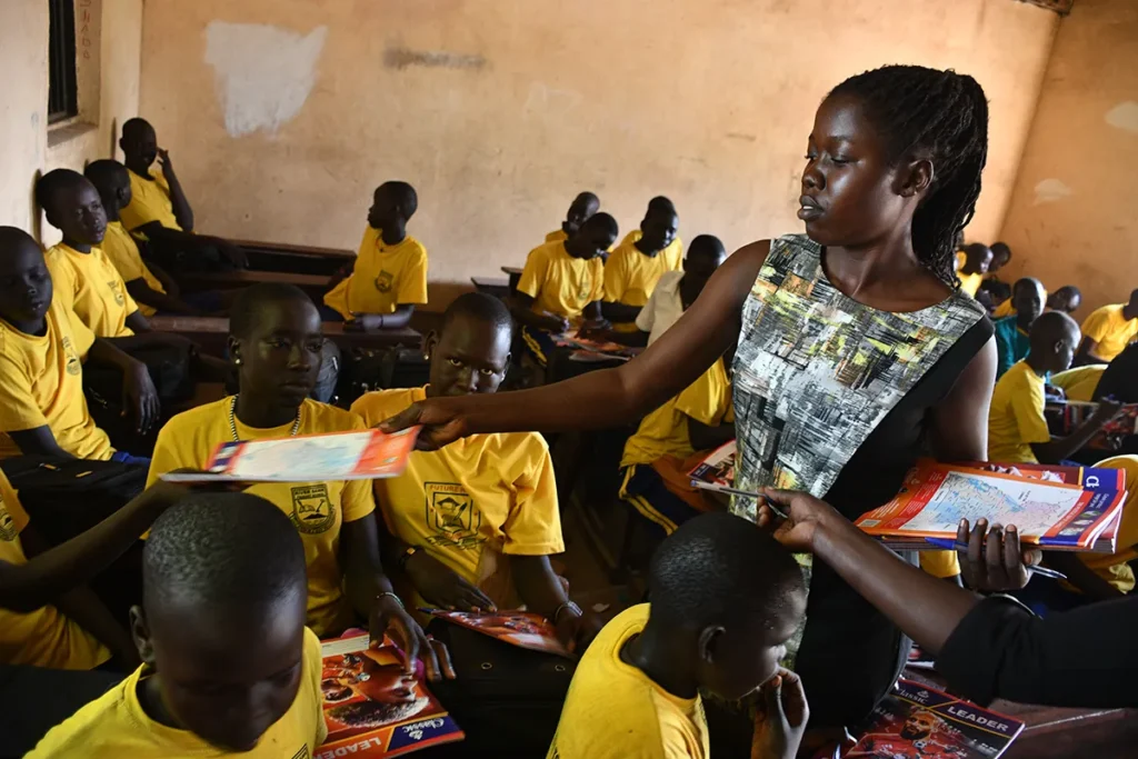 A teacher hands out books in a classroom in Nimule, South Sudan